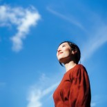 Article thumbnail: Low angle portrait of beautiful smiling young Asian woman standing against beautiful clear blue sky, looking up to sky enjoying nature and sunlight. Freedom in nature. Connection with nature