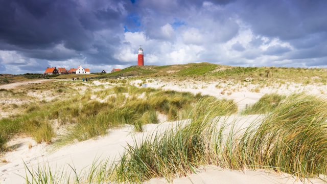 Article thumbnail: Lighthouse and houses on the north point of the island of Texel near De Cocksdorp on a stormy summer day