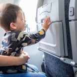 Article thumbnail: 10 months old mixed race baby boy traveling in airplane flying sitting on his mother lap in the aircraft. Infant taking airplane with his mom