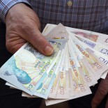 Article thumbnail: Senior male holding British bank notes in his right hand, ??50, ??20, ??10 and ??5 pound notes.